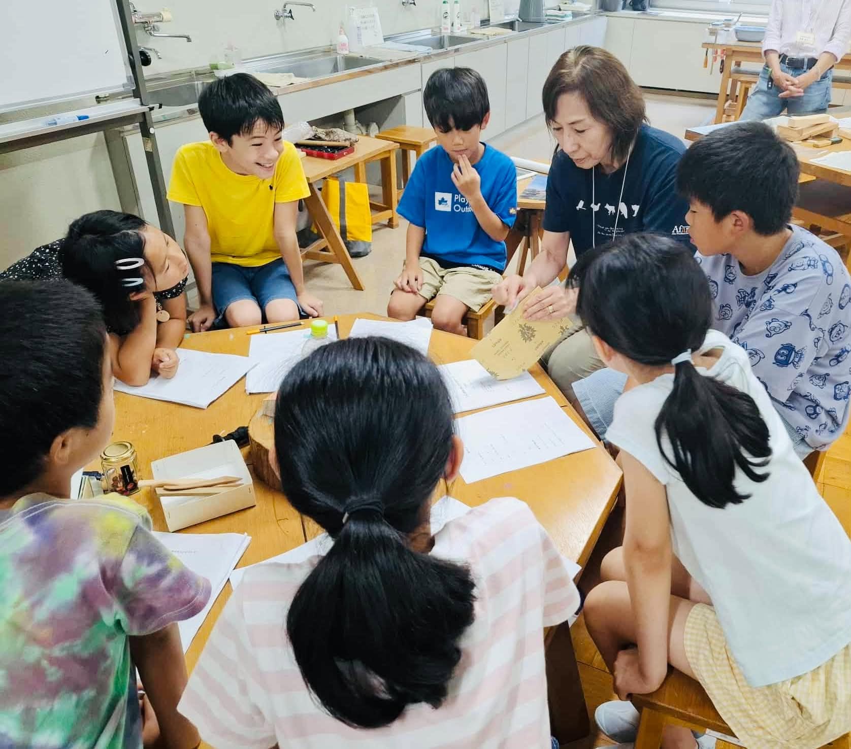 子どもと大人が一緒に木を削る